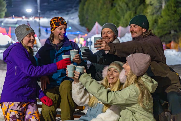 Friends toasting drinks at snowy campsite